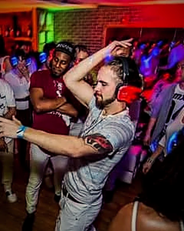 James dancing at a packed party, one arm raised
